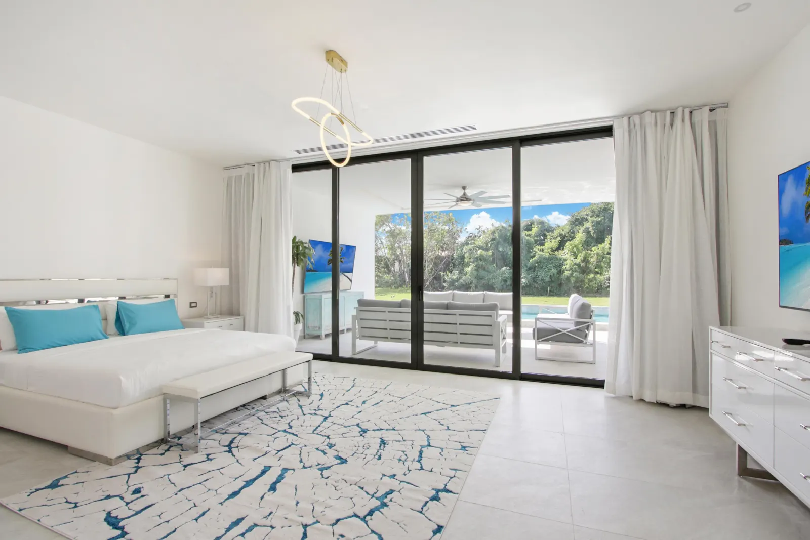 A white bedroom with glass doors onto the garden