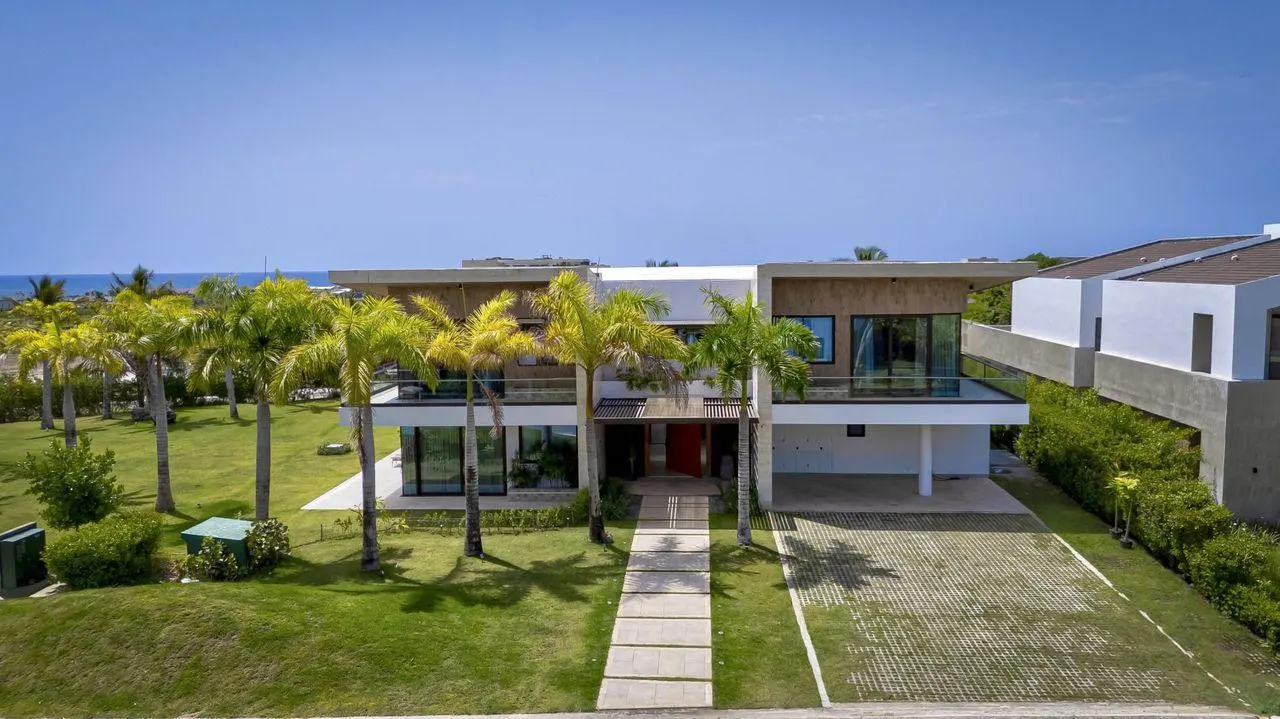 The front of the house behind its lawn and palms