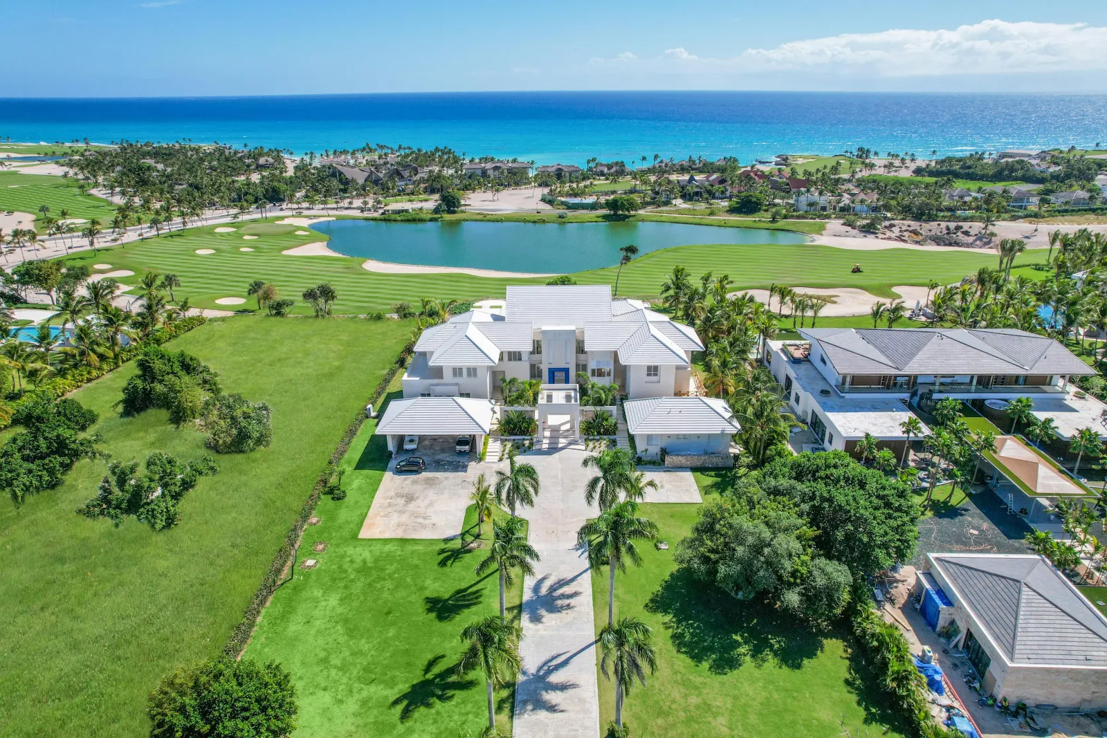 The house and its gardens from the air, the golf course, a lake and the sea beyond