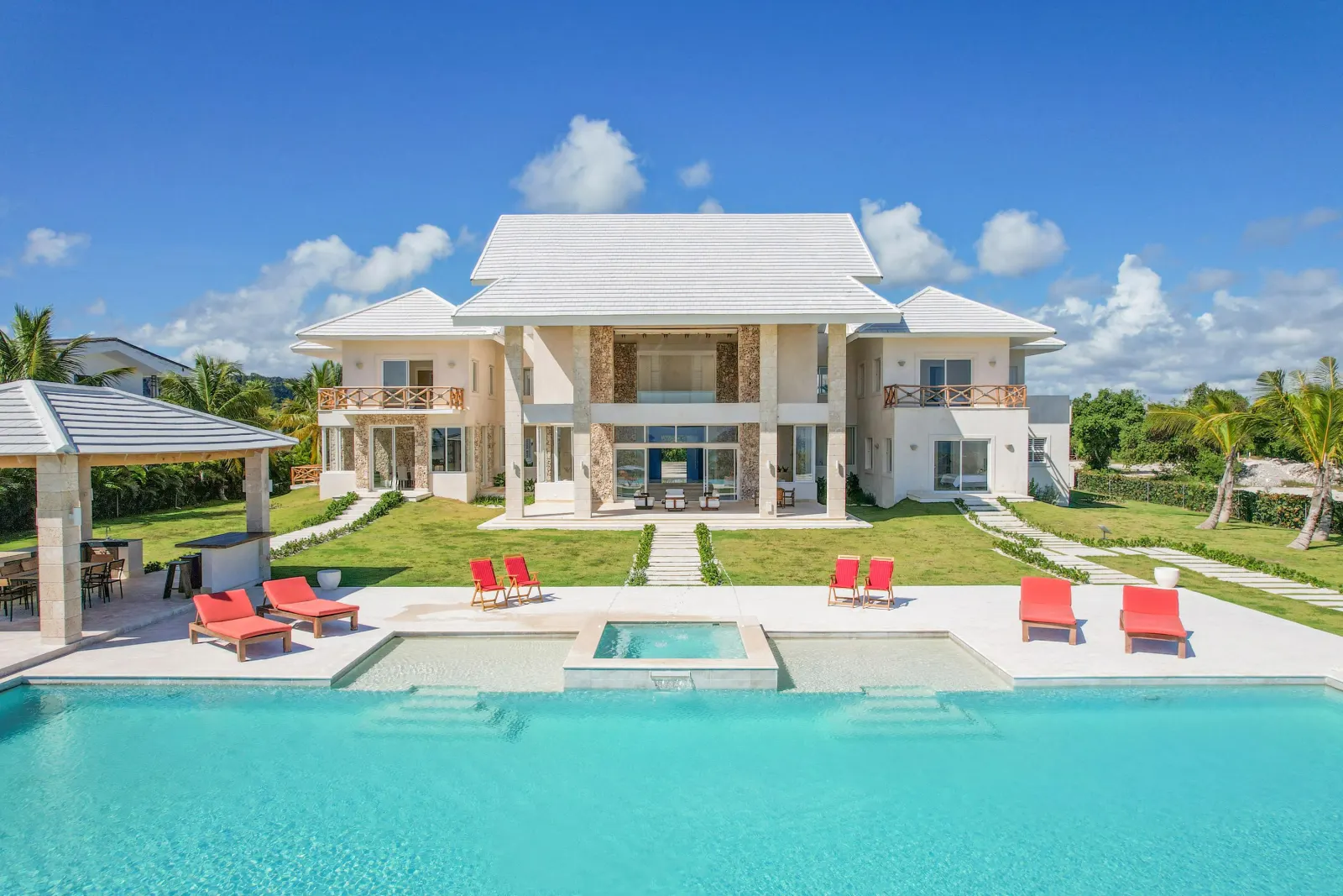 The pool before the white house, red loungers on the stone