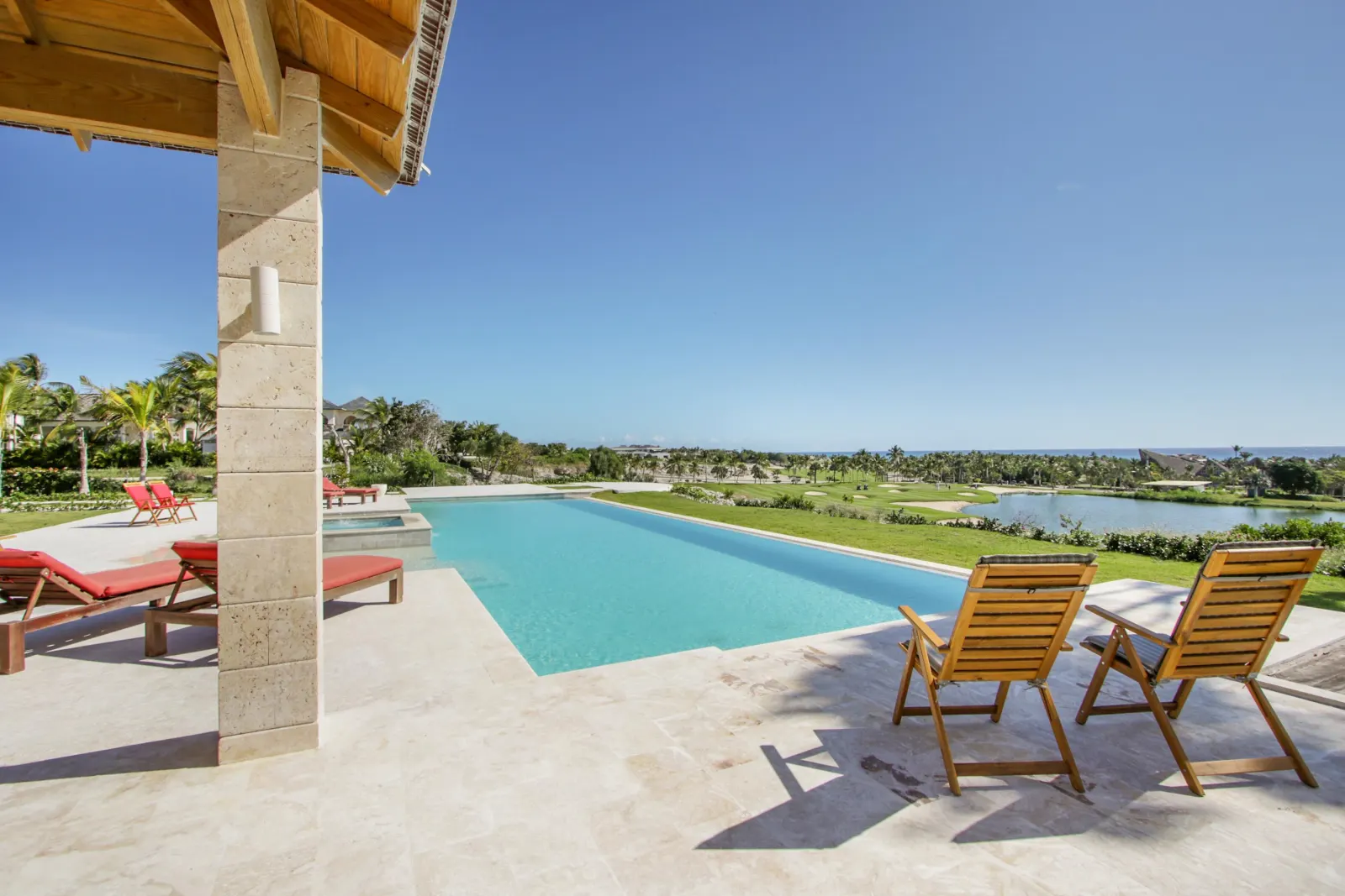 A long pool and wooden chairs looking out over the green