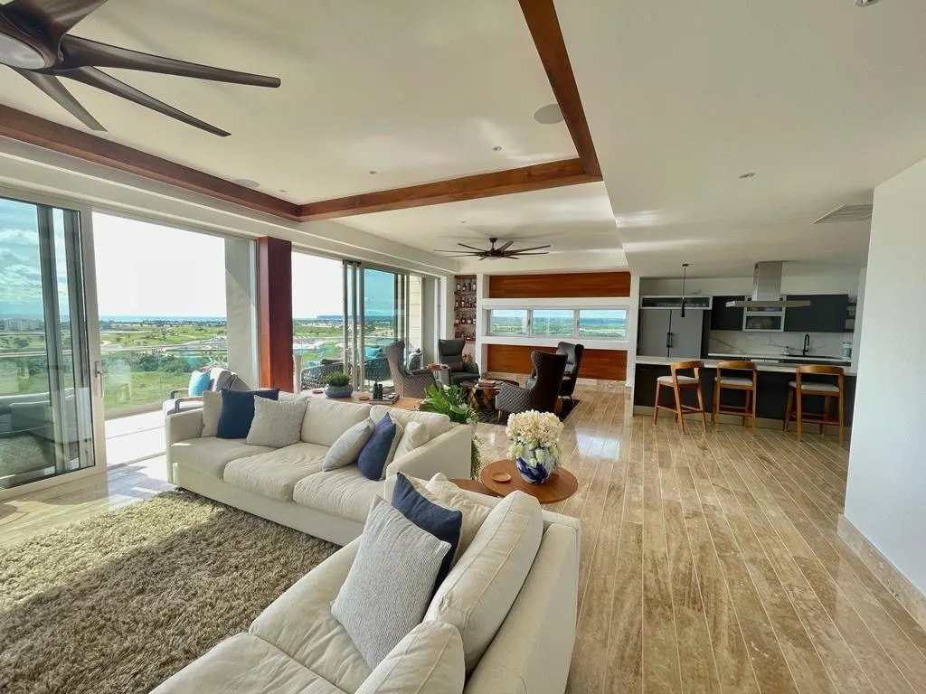 A living room with deep sofas and glass on two sides