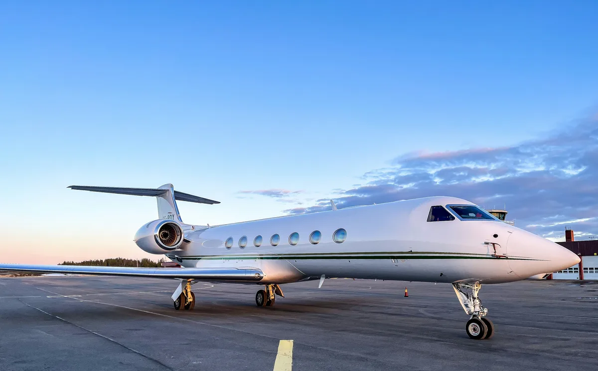 A private jet on the apron in the early light, its stairs down