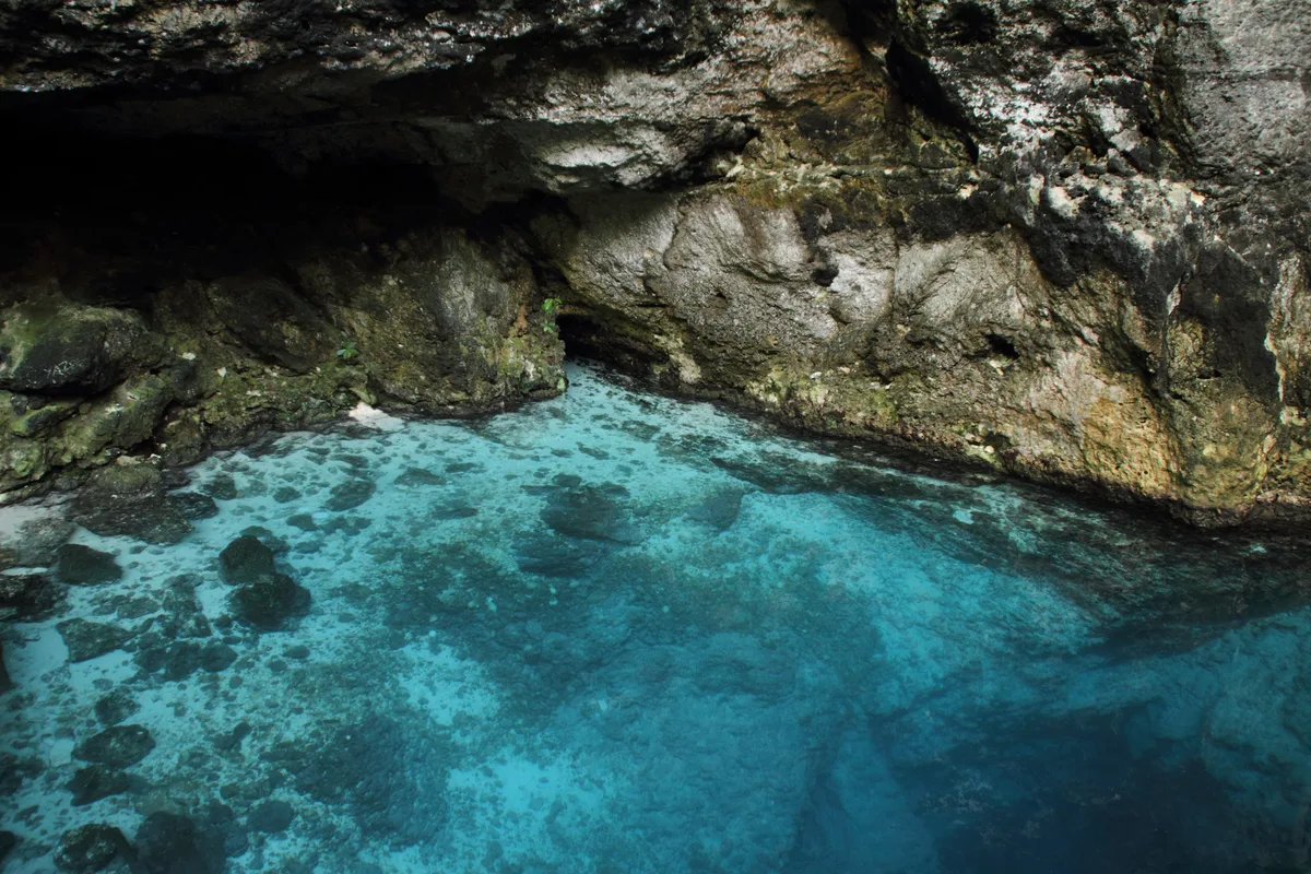 Clear turquoise water at the foot of a limestone cliff