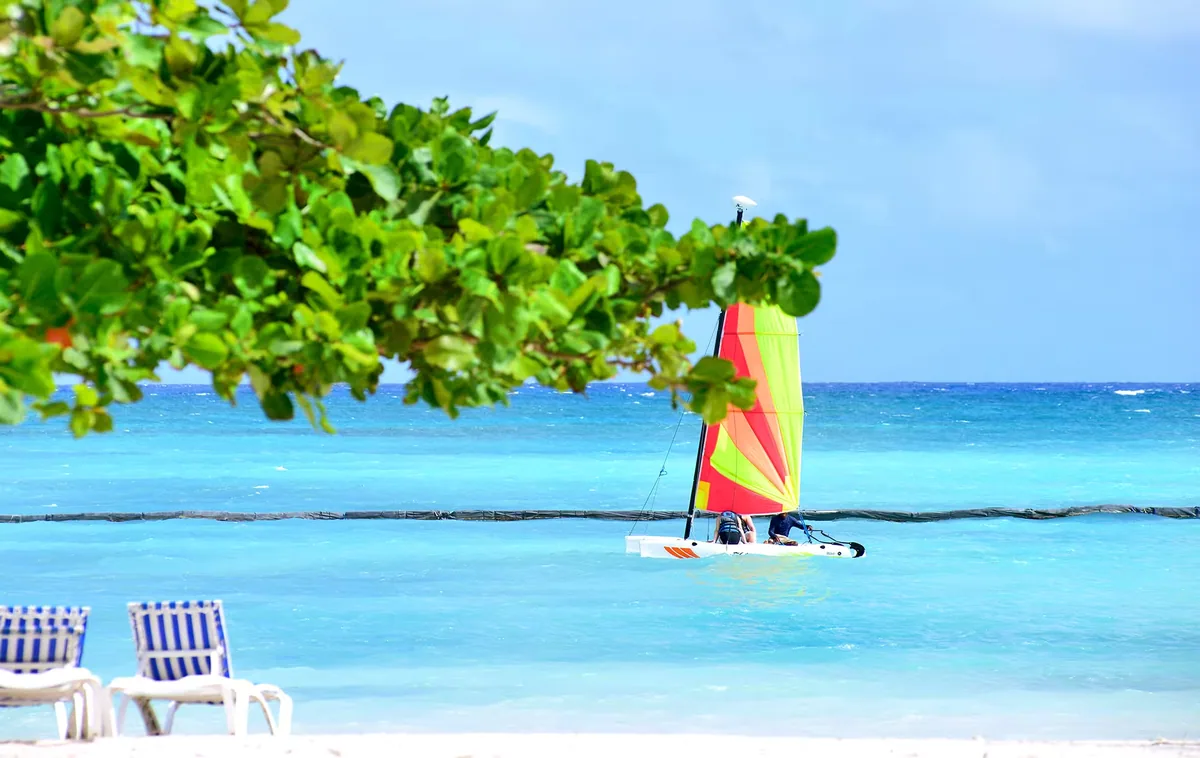 A striped sail on the turquoise water off the beach