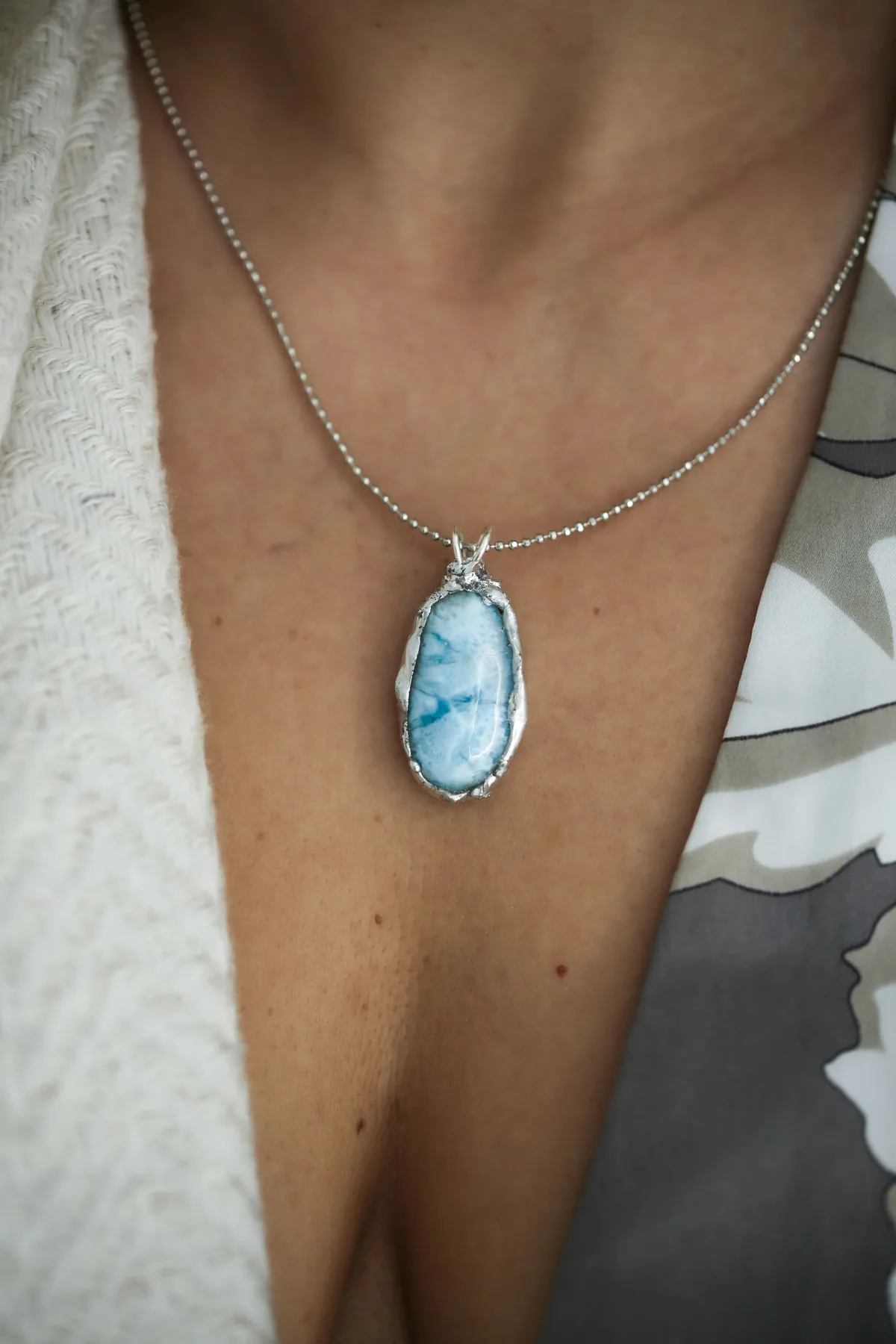 A larimar pendant worn over a white silk neckline