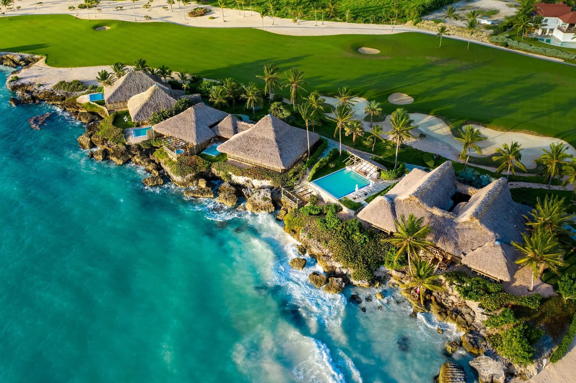Bungalows on the cliff at Eden Roc, the sea breaking below and the golf course behind