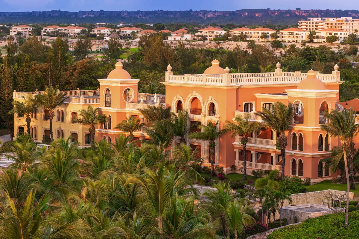 The colonial towers and roofs of Sanctuary Cap Cana seen from above among the palms